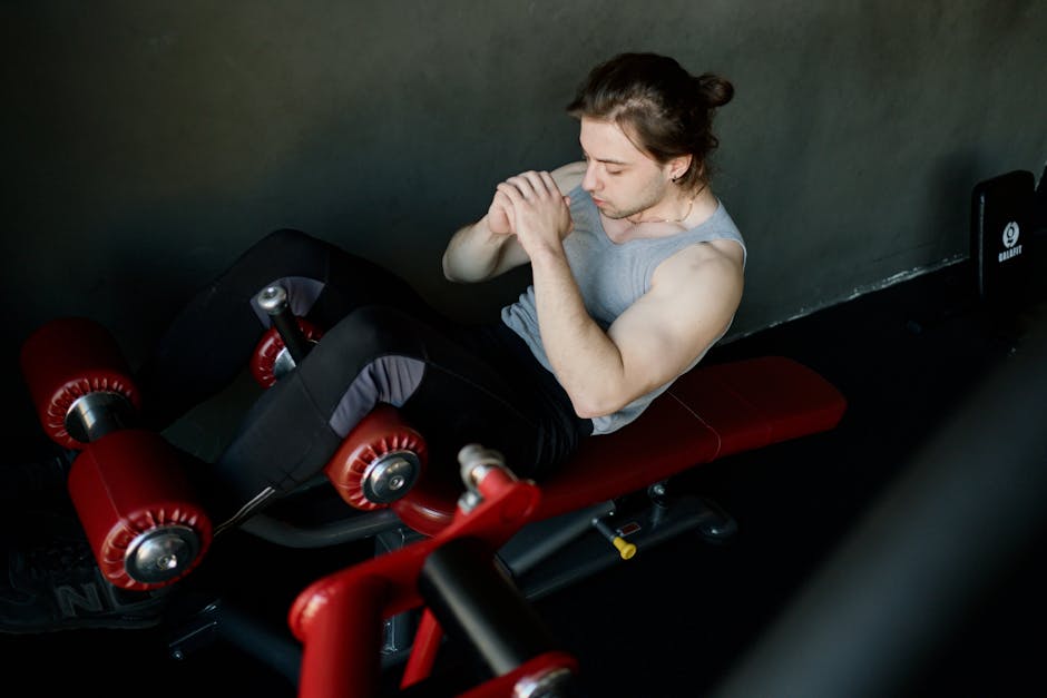 A focused man performs abdominal exercises on gym equipment, highlighting fitness and determination.