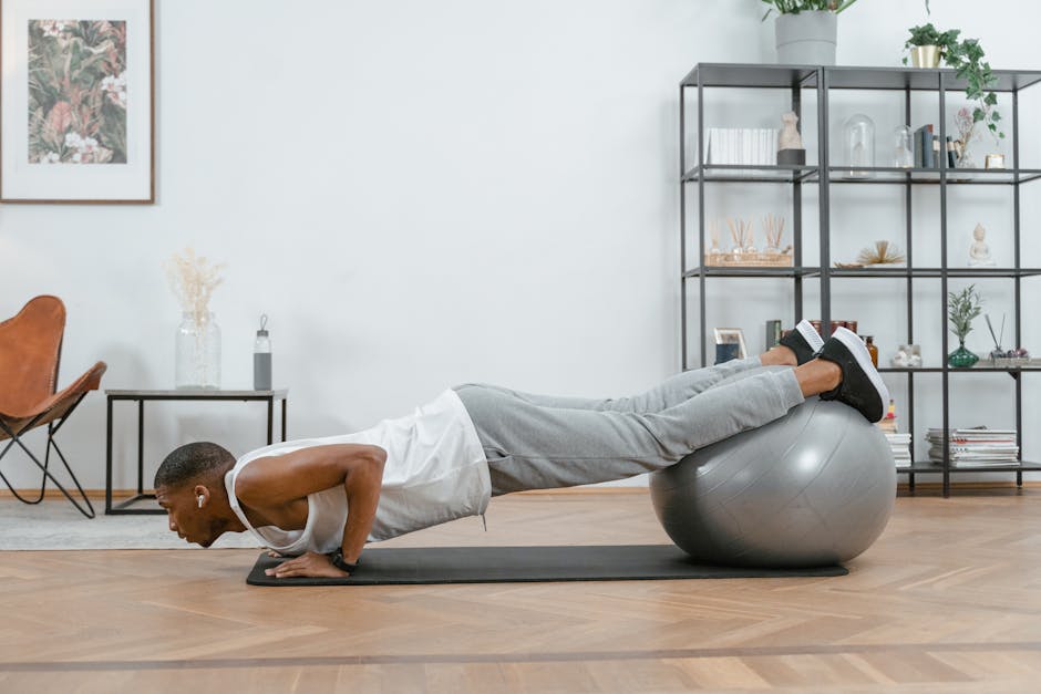 Adult doing push-ups with an exercise ball indoors for fitness and health.